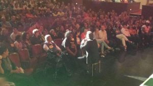 Host Todd Newton takes a seat in the front row with the two Showcase contestants—both elderly women, one with a walker. Instead of making her walk up stairs to stand behind a podium, he had them both sit with him in the front row. This kind of spontaneity makes every performance unique. Photo courtesy Todd Newton.